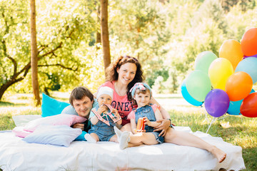 Young family with kids having picnic outdoors.