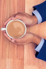 Cropped hands of businessman holding coffee cup on desk