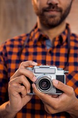 Mid section of businessman holding camera against wall in office