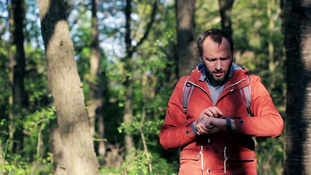 A lost young man with smartwatch looking for direction in the forest
