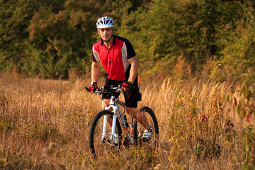 Man is riding a mountain bike in the field