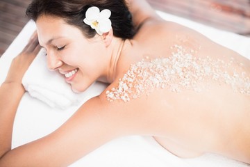 Woman lying on massage table with salt scrub on back 