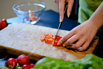  Female slicing pepper for salad. Close up chef cutting vegetabl