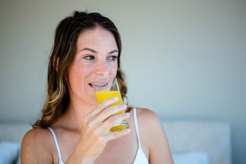 smiling woman drinking a glass of orange juice