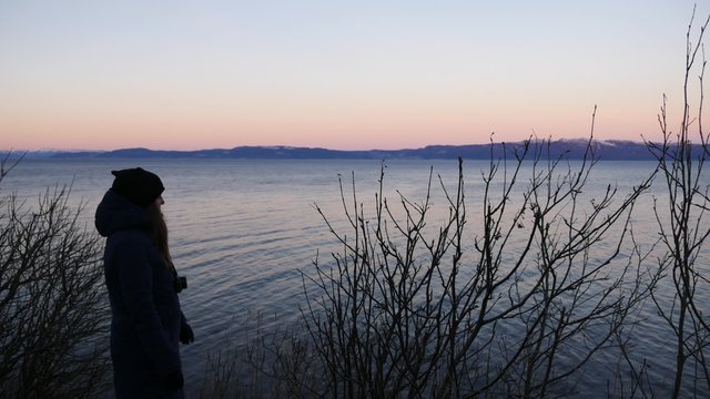 Woman traveler looking at sunset in trondheim fjord , Norway