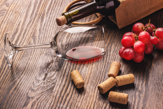 Glass with wine, bottle and bunch of grapes, wooden background