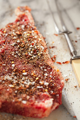 beef steak t-bone with vintage meat fork on marble backdrop