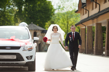 stylish gorgeous brunette bride with red bouquet and elegant gro