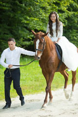 stylish gorgeous happy brunette bride riding a horse and elegant