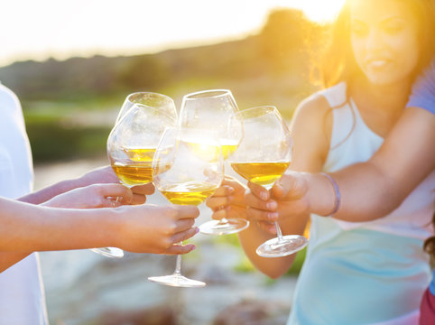 People Holding Glasses Of White Wine Making A Toast