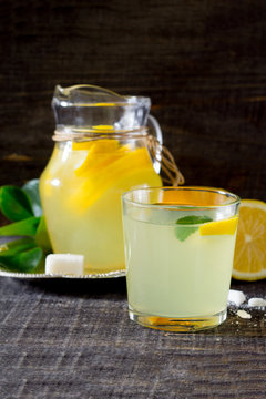 The drink of fresh lemon on a dark wooden table