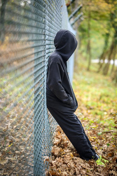 wire fence standing in front of hooded young