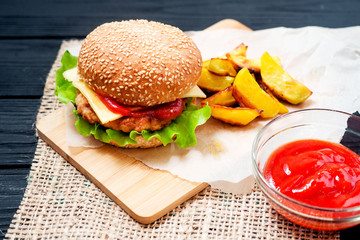 food, fast food, burgers with cheese , meat patty , lettuce, sauce , Baked potatoes and a drink , cola or beer on a wooden background