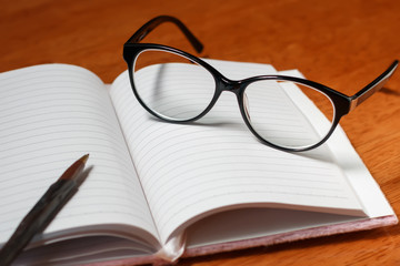 Open blank notebook, pencil and glasses