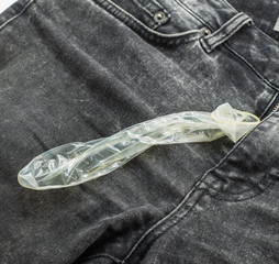 used condom,condom in the hands ,on jeans texture background.