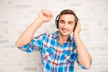 Young smiling man listening to music in headphones