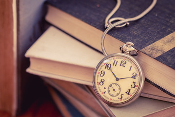 Old pocket watch on stack of books