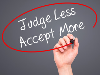 Man Hand writing Judge Less Accept More with black marker on vis
