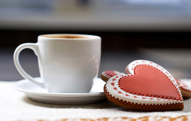 Hungry for sweets? Closeup of a glazed Valentine’s day cookie and a cup of delicious beverage at the local cafe