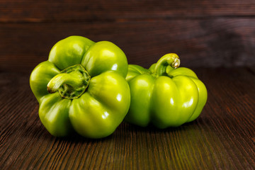 Green raw peppers on dark wooden surface