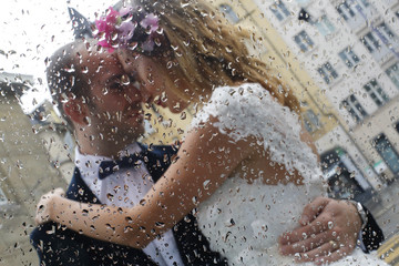 Fototapeta premium Beautiful bride and groom embracing in rain