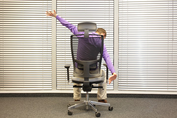 man exercising on chair in office, healthy lifestyle - back view