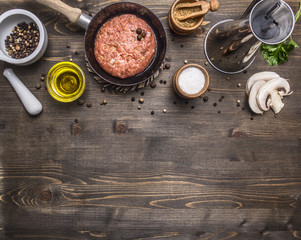 cutlet of ground beef in a small frying pan, sliced mushrooms, pepper, herbs and salt border ,place for text on wooden rustic background top view close up