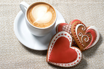 Coffee love. Top view closeup of a coffee with froth and three red heart shaped cookies