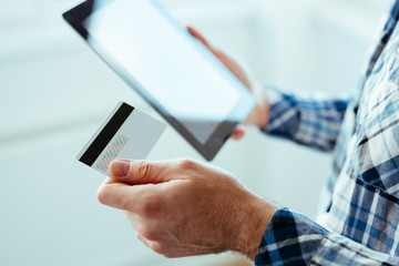male hands holding credit card and a tablet