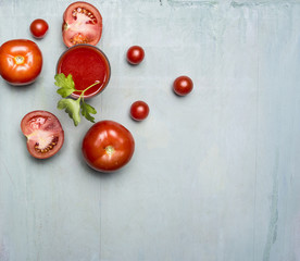 Fresh tomato juice in a glass with a straw, with green leaf, chopped tomatoes spread around border ,with text area on wooden rustic background top view close up