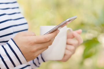 closeup female using phone and coffee drink in morning modern li