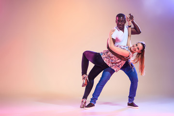 Young couple dances social Caribbean Salsa, studio shot 