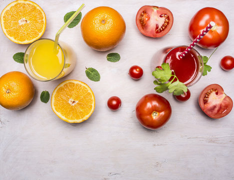 Healthy foods fresh juice in glasses with straws, oranges and tomatoes on wooden rustic background top view close up
