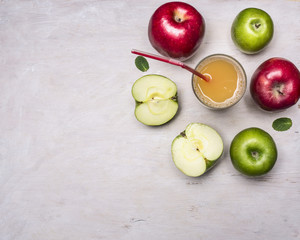 fresh apple juice, sliced apples of different varieties, with a glass of juice and a straw on wooden rustic background top view close up