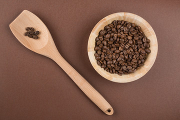 Coffee beans in bowl on brown background