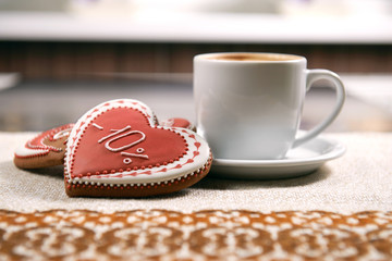 Tasty morning snack. Heart shaped decorated with glaze cookies served with a cup of warm cappuccino at the local coffee shop