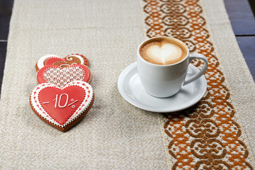 Celebrate with us. High angle shot of three heart shaped glazed cookies and a cup of frothed cappuccino