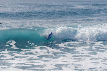 Fototapeta premium Bodyboarding and surfing in the waves of the Atlantic in front of the island La Gomera. A short light type of surfboard ridden in a prone position