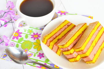 Cake on a plate, a Cup of coffee, spoon on a white wooden background