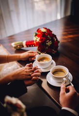 Wedding hands with bouquet and coffe