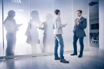 two businesspeople interacting at meeting on the background of the silhouettes of other people