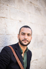 Stylish bearded man standing against of white wall and looking a