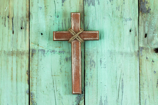 Wood cross hanging on rustic background