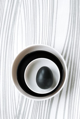 Top view of black and white dishes and en egg on waved background.