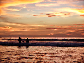 Young couple in the sea against the backdrop of a beautiful suns