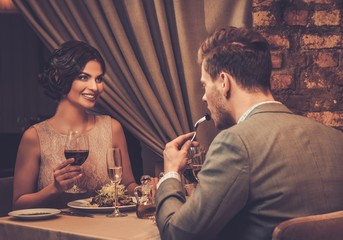 Stylish wealthy couple enjoying meal at restaurant.
