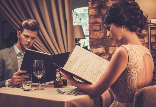 Stylish wealthy couple with menu in a restaurant.