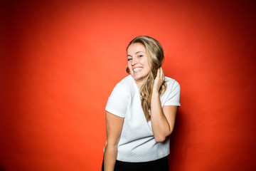 Smiling Blonde woman in studio in front of orange background