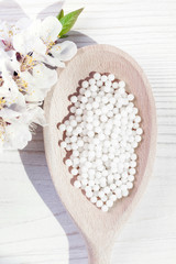 homeopathic pills on a wooden background with spring flowers