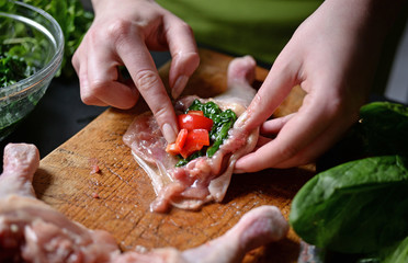 Young woman preparing chicken with vegetables